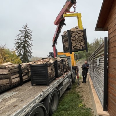 Hydraulická ruka nákladního vozu nakládá kontejnery se dřevem